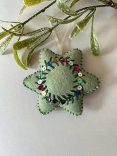 an ornament made out of felt with buttons on it and leaves in the background