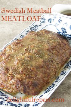 a meatloaf on a blue and white plate next to a cup of coffee