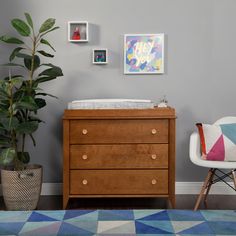 a baby crib in the corner of a room with a chair and potted plant