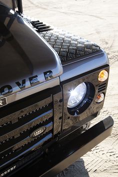 the front end of a black truck with its lights on