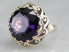 "A gorgeous purple amethyst with flashes of indigo and plenty of glitter is the centerpiece of this fabulous mid-century cocktail ring. A pierced scrolling scallop frame adds graphic interest and makes this piece unique to other ornate cocktail rings! Metal: 14K Yellow Gold Gem: Amethyst 17.69 Carats Gem Measurements: 17.2 mm, Round Ring Size: 6 Marks: \"14K\" Stamped on the inside band SKU #: N7UDRCEV Each piece has been identified and graded by a Graduate Gemologist who has been certified by t Yellow Gold Sapphire Ring, Amethyst Cocktail Ring, Rings Metal, Right Hand Ring, Vintage Cocktail Ring, Cameo Ring, Right Hand Rings, Hand Ring, Round Rings