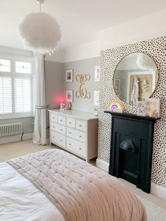 a bedroom with leopard print wallpaper and white bedding, along with a black fireplace mantel