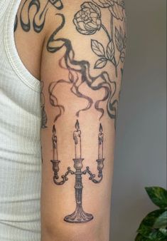 a woman's arm with a candle and rose tattoo on the left side of her arm