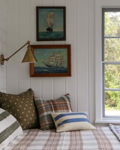 a bed with plaid sheets and pillows in front of two framed pictures on the wall