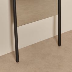 a table with two black legs and a white wall in the background