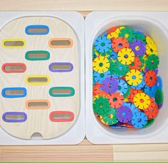 two trays filled with colorful wooden toys and one has a flower design on it