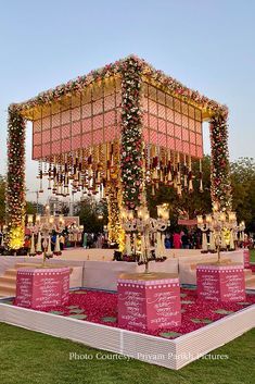 an outdoor stage decorated with flowers and candles for a wedding or other function at night