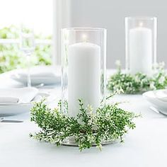 a white table setting with candles and greenery