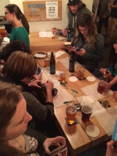 a group of people sitting at a table with beers and cell phones in their hands