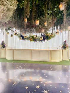 a stage set up for a wedding with stars on the floor and lights hanging from the ceiling