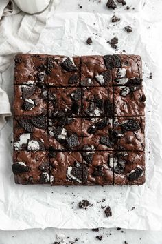 chocolate brownies with oreo cookies and milk on the side, next to a cup of coffee