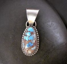 Oval turquoise stone set in oxidized sterling silver. A simple setting that features a complicated stone with abundant copper and black matrix in a soft blue field. Golden Hill, Southwestern Jewelry, Turquoise Pendant, Native American Jewelry