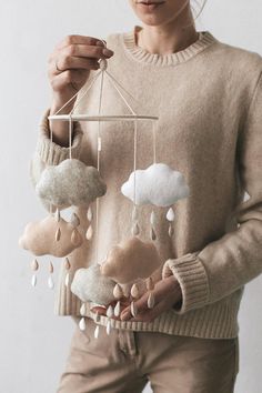 a woman holding a mobile with clouds hanging from it