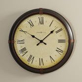 a wall clock with roman numerals on the face and brown leather strap around it