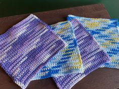 three crocheted dishcloths sitting on top of a wooden table