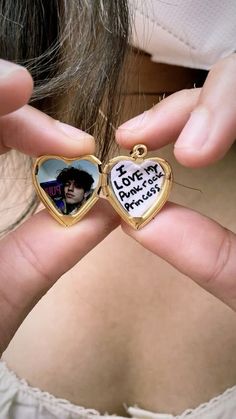 a woman holding two heart shaped pendants with a photo on it's side