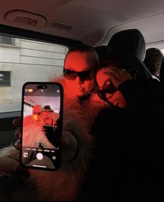 two people taking a selfie in the back seat of a car with their cell phone