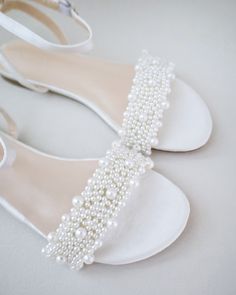 a pair of white shoes with pearls on them