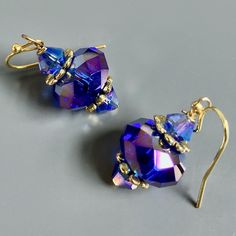 "Purple and Gold  Earrings - Glass Iridescent Purple  Beads with Gold Plated Beadcaps and Iridescent Purple Bacon Glass Beads. These earrings have a lot of sparkle and are gorgeous when the light hits them. The Beads are approximately 14mm wide Gold plated Earwires Earrings measure  1.25\" long from top of earwire to bottom" Purple And Gold Earrings, Elegant Iridescent Crystal Earrings Gift, Adjustable Iridescent Drop Earrings, Elegant Iridescent Crystal Earrings, Handmade Iridescent Crystal Earrings For Party, Party Jewelry With Iridescent Ear Wire, Iridescent Teardrop Earrings For Wedding, Handmade Adjustable Crystal Earrings For Party, Iridescent Party Earrings