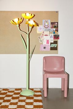 a pink chair sitting next to a flower in a vase on top of a table