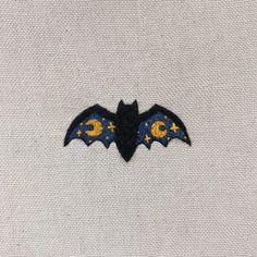 a bat embroidered onto a white shirt with yellow and blue stars on the chest pocket