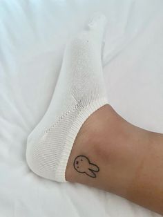 a person's foot with a small tattoo on their left leg, and a white sock