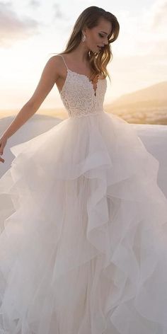 a woman in a wedding dress standing on the beach