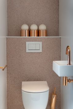 a white toilet sitting in a bathroom next to a wall mounted faucet and sink