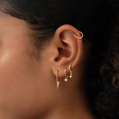 a woman wearing gold ear cuffs with two small stars on the end of each ear