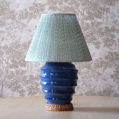 a blue lamp sitting on top of a table next to a wallpapered wall