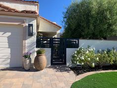 a house with two large planters in front of it and a driveway leading to the back door