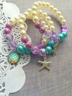 two bracelets with beads and charms on top of a doily