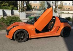 an orange sports car with its doors open