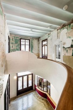 a curved staircase in the middle of a room with two windows and no one on it