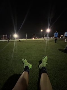 the legs and feet of a person on a soccer field at night