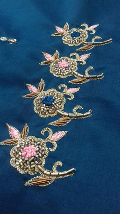 three pieces of blue fabric with pink flowers and leaves on the side, all embroidered in gold thread