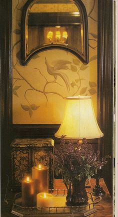 a table topped with candles next to a mirror and vase filled with flowers on top of it