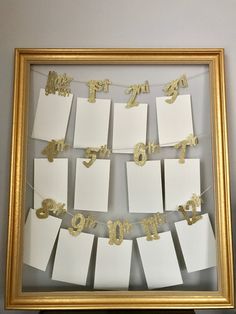 a gold frame with some white cards hanging from it's sides and numbers on them