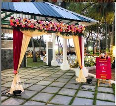 an outdoor ceremony with flowers on the canopy