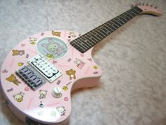 a pink guitar with hello kitty stickers on it's body and neck, sitting on a white surface