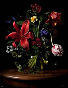 a vase filled with lots of flowers on top of a wooden table in front of a black background