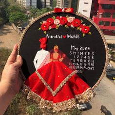 a hand holding up a black and red clock with pictures on it's face