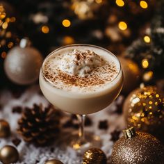 a close up of a drink in a glass on a table next to christmas decorations