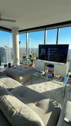 a living room filled with furniture and large windows overlooking the cityscape in the distance