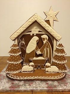 a nativity scene made out of gingerbread and decorated with white icing on a wooden table