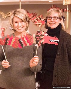 two women standing next to each other holding up paper dragon puppets in front of them