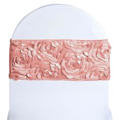 a white chair with pink roses on the back and an orange sash around it's edge