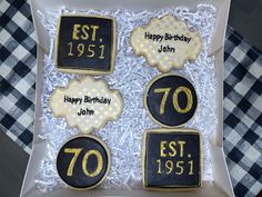 four decorated cookies in the shape of 70th birthday cookies with black and gold icing