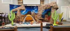 a room with some decorations on the wall and chairs in front of it that are set up to look like a desert scene