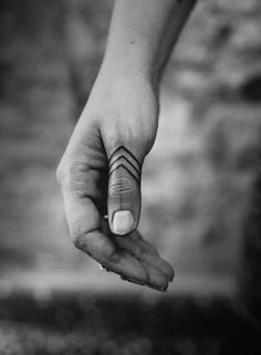 a woman's hand with a small arrow tattoo on her left thumb and finger